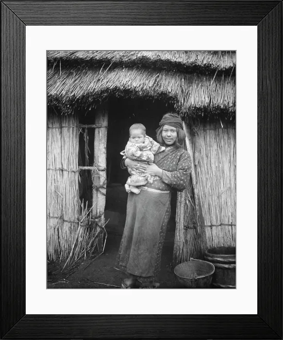Framed Print : Ainu woman holding a child standing outside a hut, 1908. Creator: Arnold Genthe Framed Print : Ainu woman holding a child standing outside a hut, 1908. Creator: Arnold Genthe