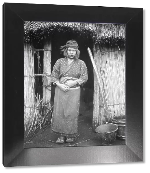 Ainu woman standing by the doorway of a hut, 1908. Creator: Arnold Genthe