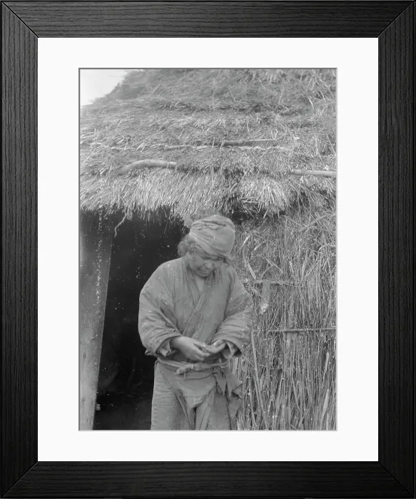 Framed Print : Ainu woman standing outside the entrance of a hut, 1908. Creator: Arnold Genthe Framed Print : Ainu woman standing outside the entrance of a hut, 1908. Creator: Arnold Genthe