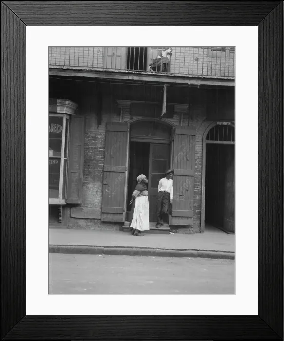 Framed Print : View from across street of a man and woman standing by a doorway and a woman seated...c1920-1926. Creator: Arnold Genthe Framed Print : View from across street of a man and woman standing by a doorway and a woman seated...c1920-1926. Creator: Arnold Genthe