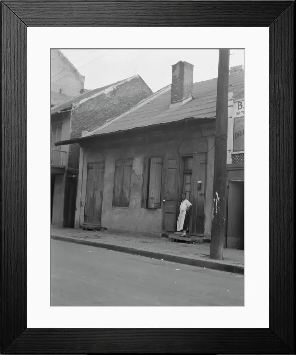 Framed Print : View from across street of a woman standing by a doorway in the French Quarter, New... c1920-c1926. Creator: Arnold Genthe Framed Print : View from across street of a woman standing by a doorway in the French Quarter, New... c1920-c1926. Creator: Arnold Genthe