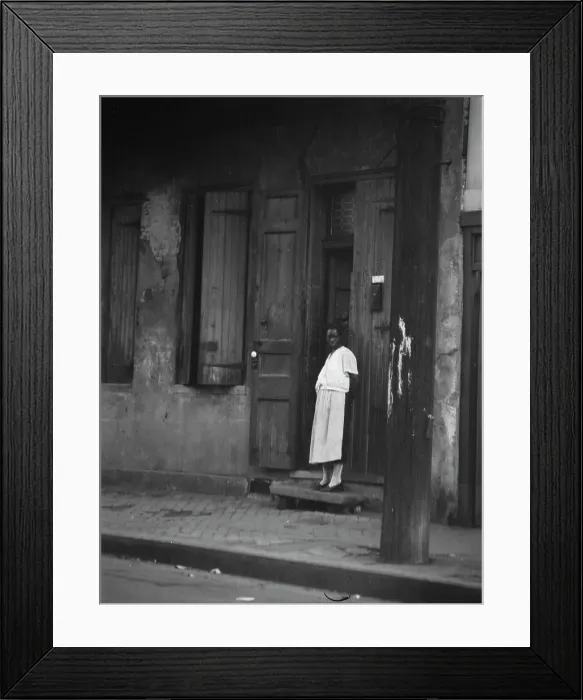 Framed Print : View from across street of a woman standing in a doorway in the French Quarter, New... c1920-c1926. Creator: Arnold Genthe Framed Print : View from across street of a woman standing in a doorway in the French Quarter, New... c1920-c1926. Creator: Arnold Genthe