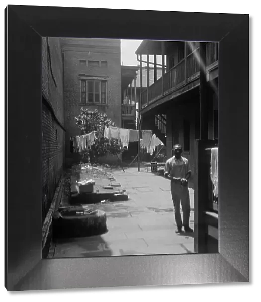 Man standing in a courtyard, New Orleans, between 1920 and 1926. Creator: Arnold Genthe
