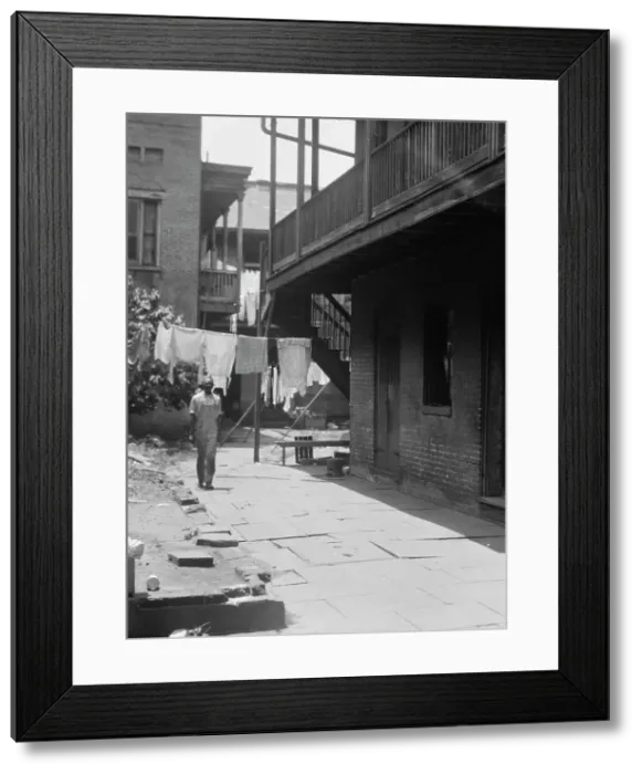 Framed Print : Man standing in a courtyard, New Orleans, between 1920 and 1926. Creator: Arnold Genthe Framed Print : Man standing in a courtyard, New Orleans, between 1920 and 1926. Creator: Arnold Genthe