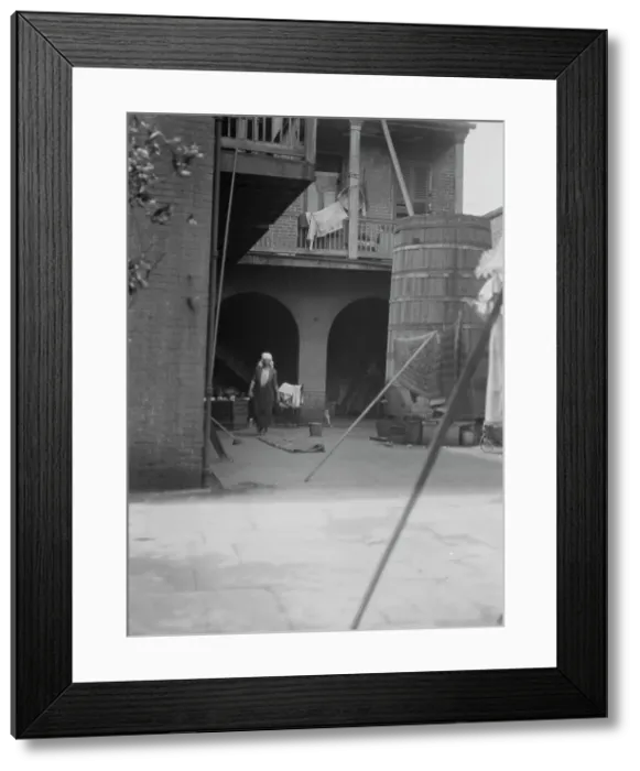 Framed Print : Courtyard with cistern and woman cleaning, New Orleans, between 1920 and 1926. Creator: Arnold Genthe Framed Print : Courtyard with cistern and woman cleaning, New Orleans, between 1920 and 1926. Creator: Arnold Genthe