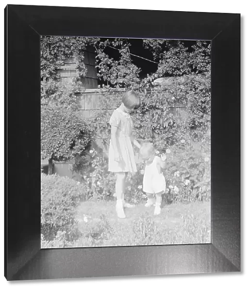 Children of Mrs. George Eustis standing outdoors in a garden, between 1911 and 1942. Creator: Arnold Genthe