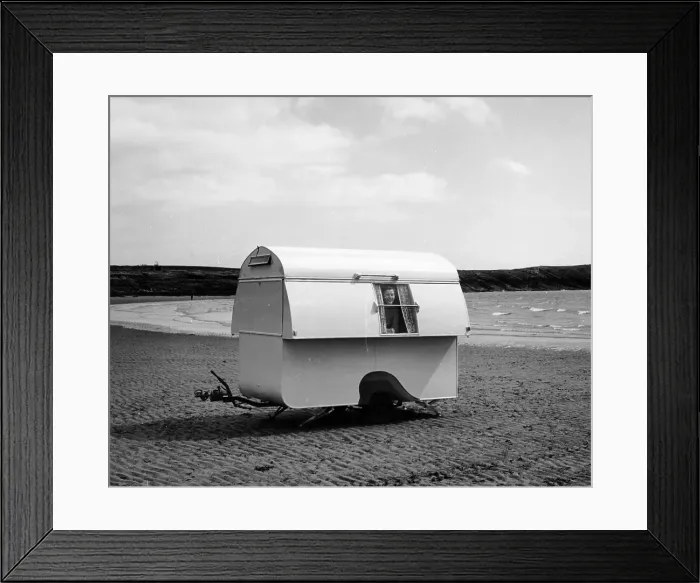 Framed Print : Woman smiling from the window of a trailer caravan on a beach, (c1960s?) Framed Print : Woman smiling from the window of a trailer caravan on a beach, (c1960s?)