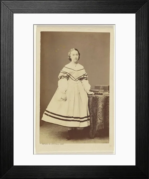 Framed Print : Unidentified woman standing near a table with books on top, 1865-1875. Creator: Bayard & Bertall Framed Print : Unidentified woman standing near a table with books on top, 1865-1875. Creator: Bayard & Bertall