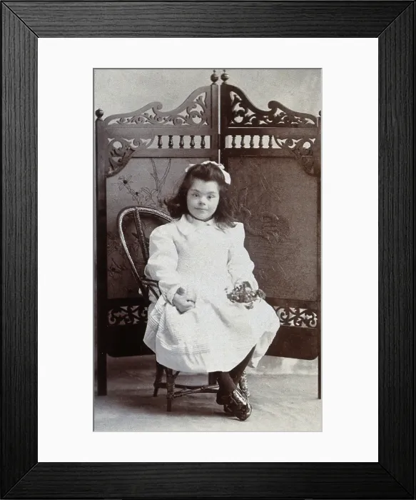 Framed Print : A girl with Down's syndrome, sitting in front of an ornate wooden screen... c1870s Framed Print : A girl with Down's syndrome, sitting in front of an ornate wooden screen... c1870s