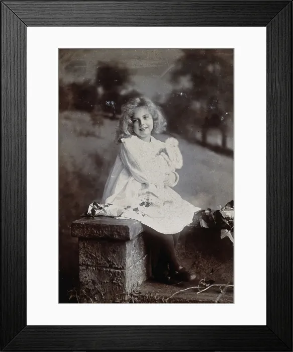 Framed Print : A girl, holding a doll, sitting on a wall, c1890s. Creator: Lock & Whitfield Framed Print : A girl, holding a doll, sitting on a wall, c1890s. Creator: Lock & Whitfield
