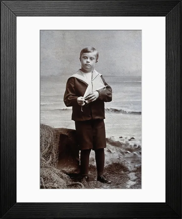 Framed Print : A boy with Down's syndrome, dressed in a sailor suit, standing against a nautical Framed Print : A boy with Down's syndrome, dressed in a sailor suit, standing against a nautical