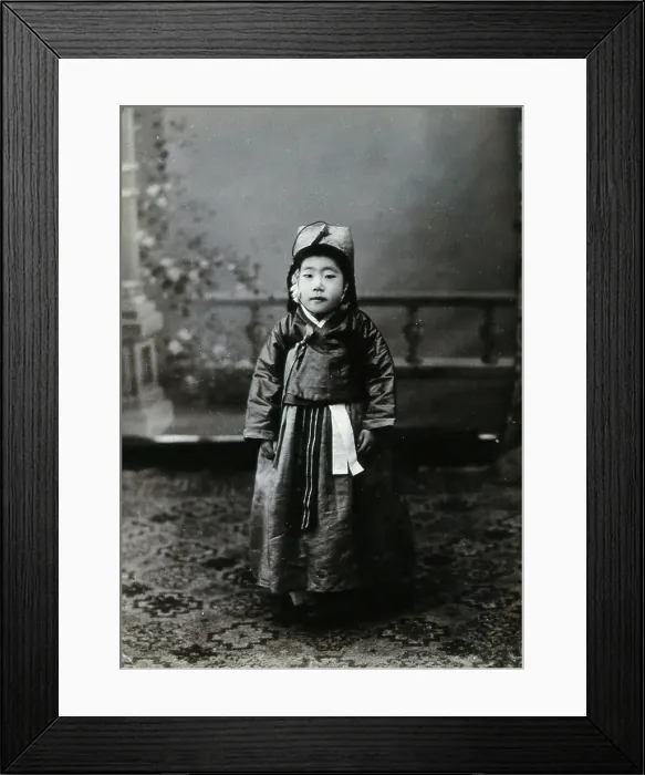 Framed Print : A child posing in front of a painted backdrop in a photographic studio, c1900. Creator: Unknown Framed Print : A child posing in front of a painted backdrop in a photographic studio, c1900. Creator: Unknown
