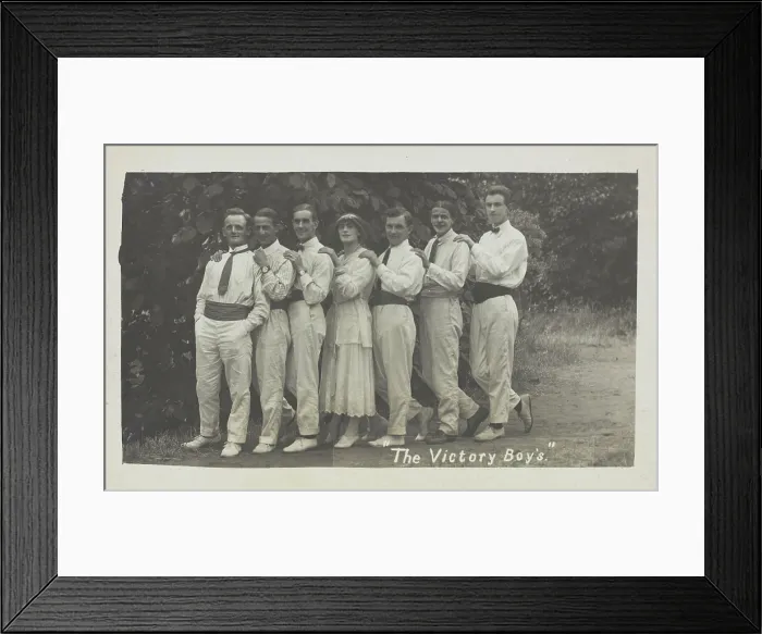 Framed Print : Entertainers, one in drag, pose in a line in front of foliage, [between 1910 and 1919?]. Creator: Unknown