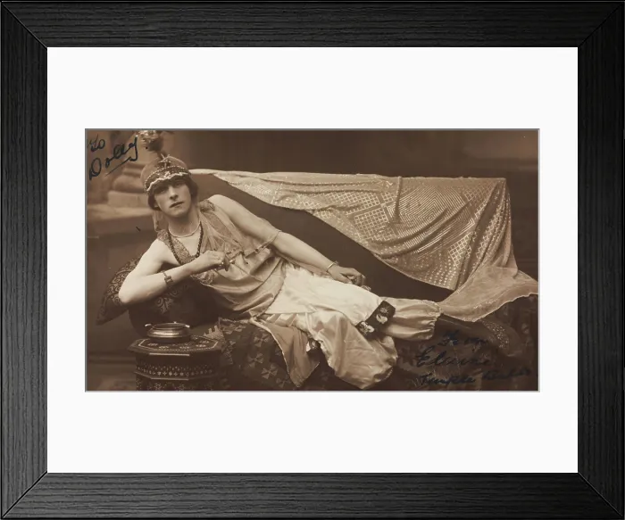 Framed Print : A man in drag poses wearing delicate attire; curled up on a piece of furniture, [1910-1919?]. Creator: Unknown