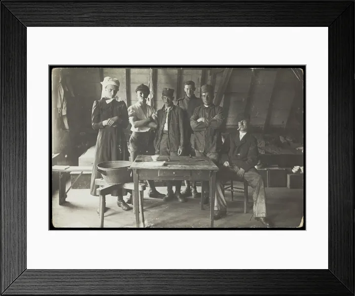 Framed Print : French prisoners of war, one in drag, gather round a small wooden table, [between 1910 and 1919?]. Creator: Unknown