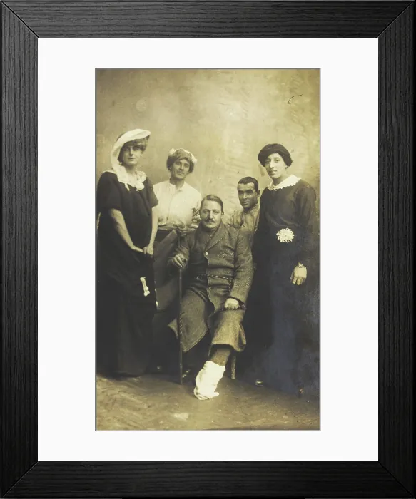 Framed Print : Four soldiers posing, three in drag, with an injured soldier seated in the centre, [1910-1919?]. Creator: Unknown