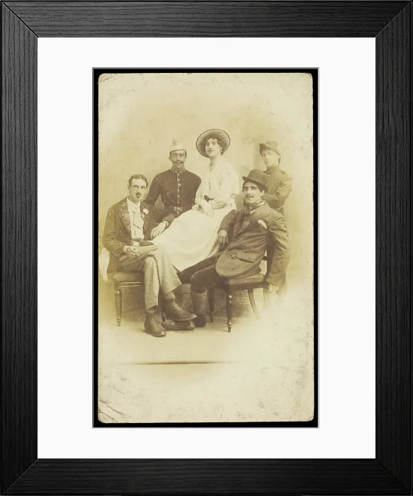 Framed Print : Amateur actors sitting down, surrounding a man in drag seated in the centre, [1910-1919?]. Creator: Unknown