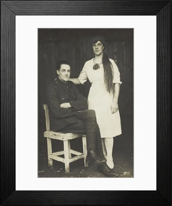 Framed Print : Two prisoners of war, one in drag, pose with a chair, [between 1910 and 1919?]. Creator: Unknown