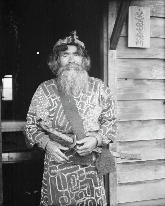 Framed Print : Ainu chief wearing a headdress and holding a sword standing in a doorway, 1908. Creator: Arnold Genthe Framed Print : Ainu chief wearing a headdress and holding a sword standing in a doorway, 1908. Creator: Arnold Genthe