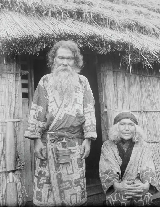 Framed Print : Ainu man and seated woman at the entrance of a hut, 1908. Creator: Arnold Genthe Framed Print : Ainu man and seated woman at the entrance of a hut, 1908. Creator: Arnold Genthe