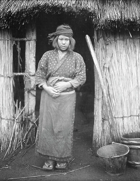 Ainu woman standing by the doorway of a hut, 1908. Creator: Arnold Genthe
