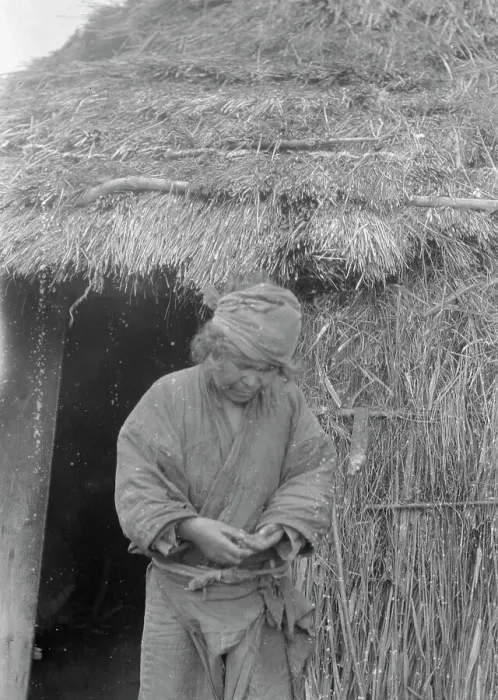 Framed Print : Ainu woman standing outside the entrance of a hut, 1908. Creator: Arnold Genthe Framed Print : Ainu woman standing outside the entrance of a hut, 1908. Creator: Arnold Genthe
