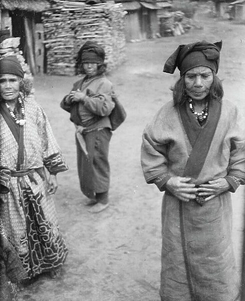 Three Ainu women outside in the village lane, 1908. Creator: Arnold Genthe