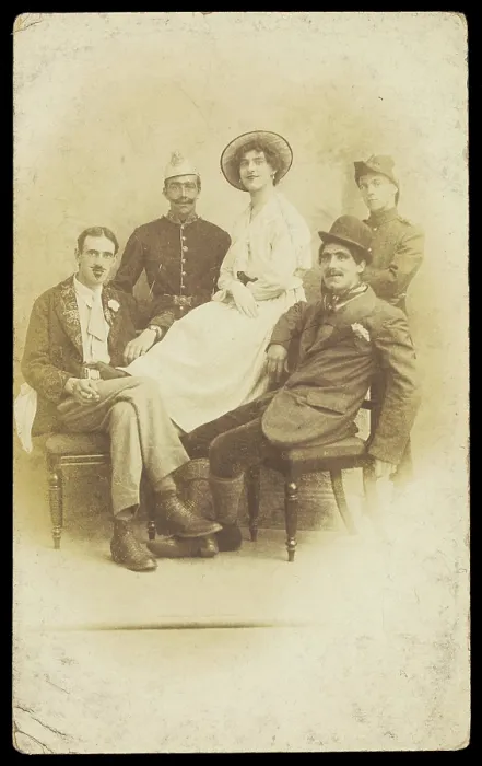 Framed Print : Amateur actors sitting down, surrounding a man in drag seated in the centre, [1910-1919?]. Creator: Unknown