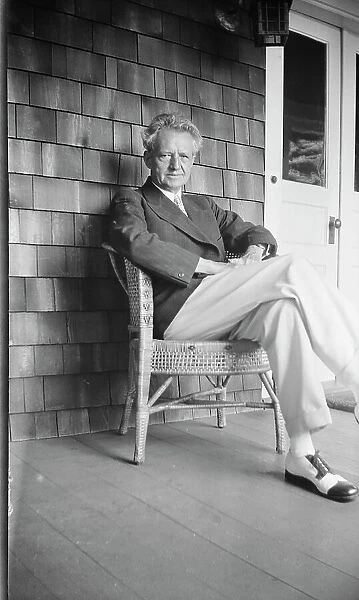 Arnold Genthe seated in a chair on a porch, between 1911 and 1942. Creator: Arnold Genthe