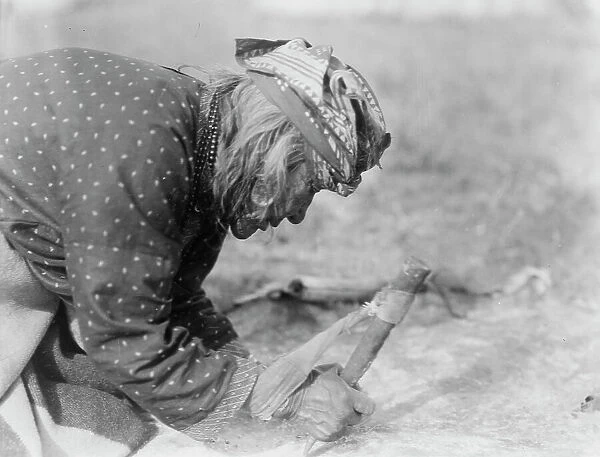 Blackfoot Indian fleshing a hide, c1927. Creator: Edward Sheriff Curtis