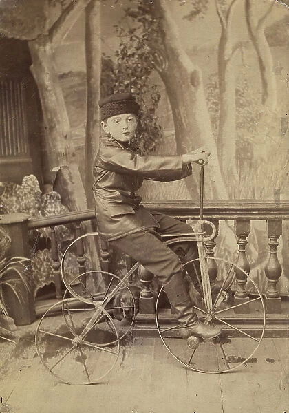 A boy on a bicycle in a photo studio, 1880. Creator: Unknown