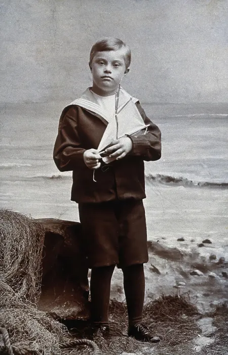 Framed Print : A boy with Down's syndrome, dressed in a sailor suit, standing against a nautical Framed Print : A boy with Down's syndrome, dressed in a sailor suit, standing against a nautical