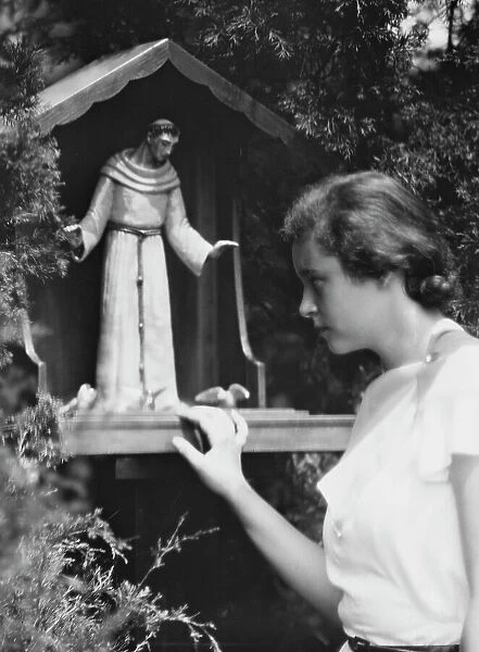 Brady, Victoria, Miss, with a statue of St. Francis in a garden, 1931 July 14. Creator: Arnold Genthe