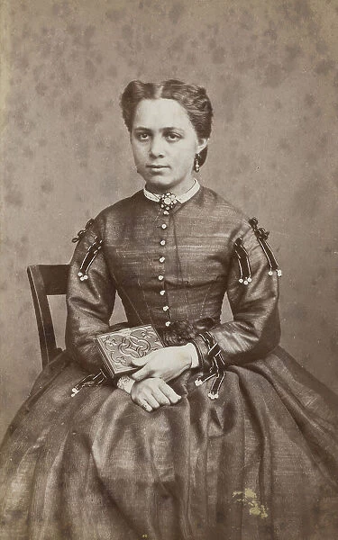 Business card, studio portrait of woman holding a photo album. (c1880s) Creator: Karolina Christianson