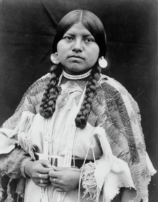 Framed Print : Cayuse woman, half-length portrait, standing, facing front, braids, shell disk earrings... c1910. Creator: Edward Sheriff Curtis