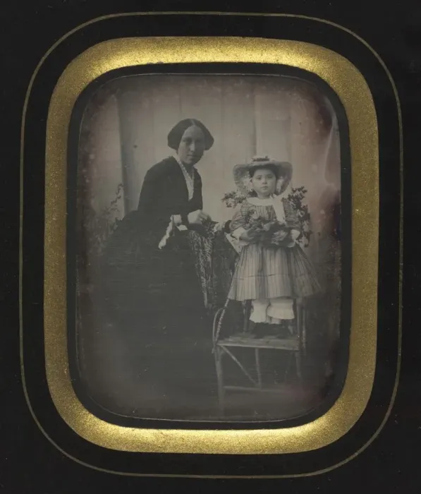 Framed Print : Child Standing on a Chair Holding Flowers, with Mother, c Framed Print : Child Standing on a Chair Holding Flowers, with Mother, c