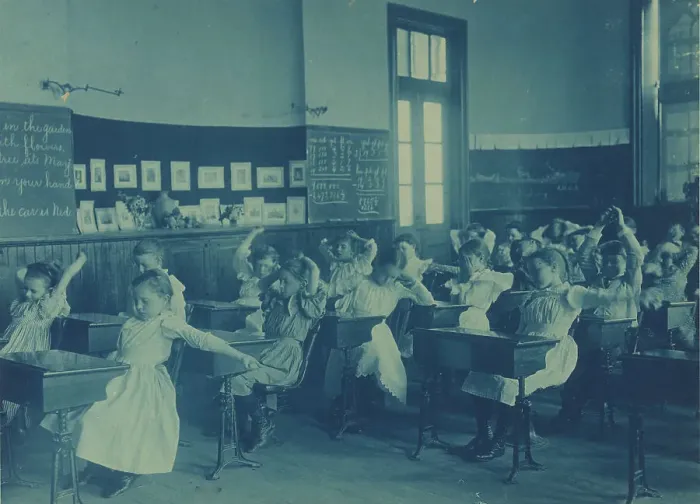Framed Print : Children doing calisthenics while sitting at their desks in a classroom... Washington, DC, (1899?). Creator: Frances Benjamin Johnston Framed Print : Children doing calisthenics while sitting at their desks in a classroom... Washington, DC, (1899?). Creator: Frances Benjamin Johnston