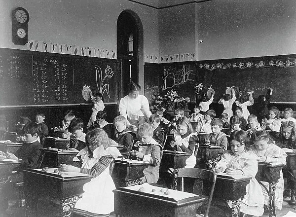 Children modeling clay at desks and drawing on blackboard in Washington, D.C. classroom, (1899?). Creator: Frances Benjamin Johnston