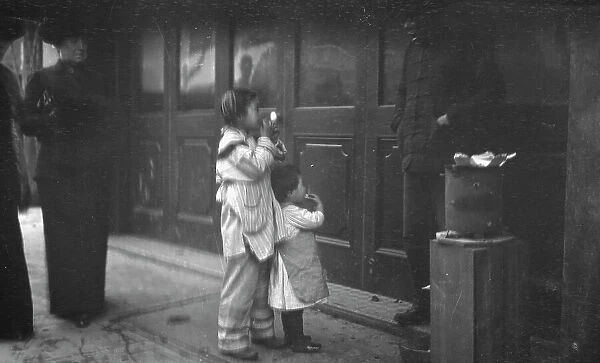 Two children standing on a sidewalk eating, Chinatown, San Francisco, between 1896 and 1906. Creator: Arnold Genthe