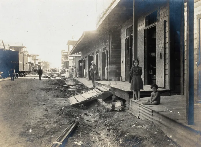 Framed Print : Colon, Panama: unpaved street lined with wooden houses; two children watch from a porch... 1906. Creator: Unknown