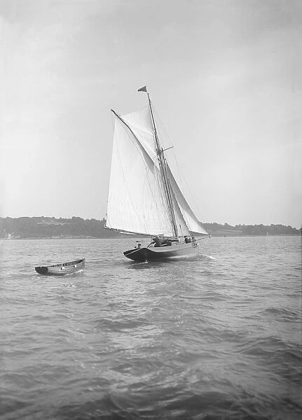 The cutter Citara under sail and towing tender, 1911. Creator: Kirk & Sons of Cowes