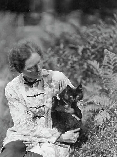 Egger, Gabrielle, Miss, friend of, with cat, seated outdoors, between 1926 and 1930. Creator: Arnold Genthe