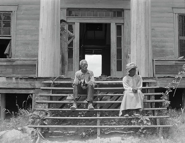 Ex-slave and wife on steps of plantation house now in decay, Greene County, Georgia, 1937. Creator: Dorothea Lange