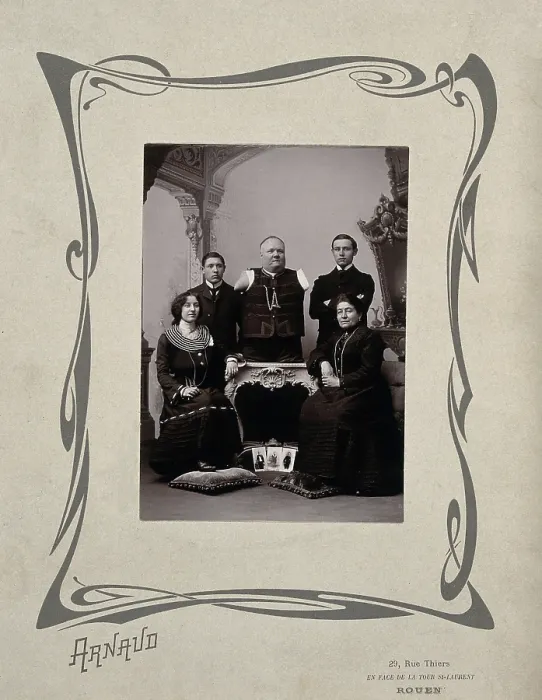 Framed Print : A family portrait: a man without arms and legs poses on a table surrounded by family, 20th Century. Creator: Unknown Framed Print : A family portrait: a man without arms and legs poses on a table surrounded by family, 20th Century. Creator: Unknown