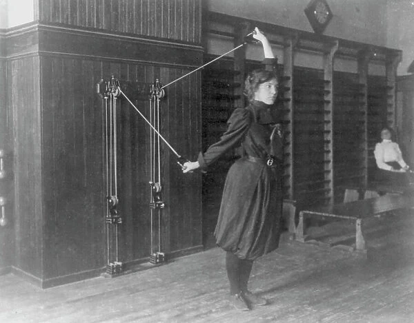 Female student exercising with a wall-mounted device using ropes and... Washington, DC, (1899?). Creator: Frances Benjamin Johnston