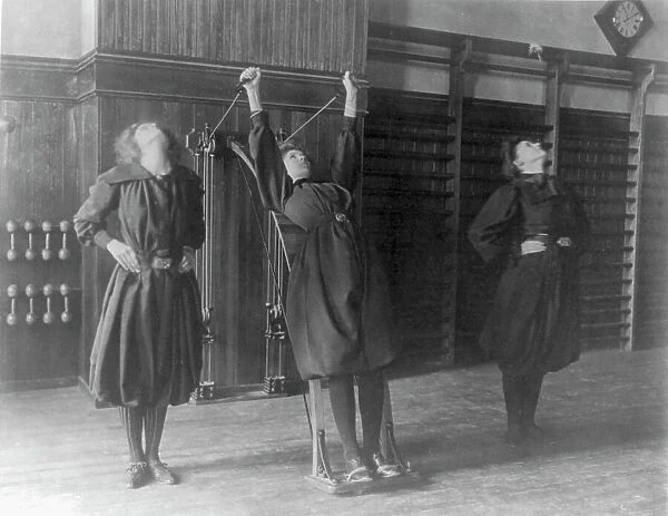 Female students exercising, one with a wall-mounted device using ropes... Washington, D.C. (1899?) Creator: Frances Benjamin Johnston