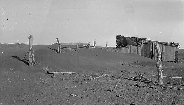 Fence corner and outbuilding being buried by dust, Mills, New Mexico, 1935. Creator: Dorothea Lange