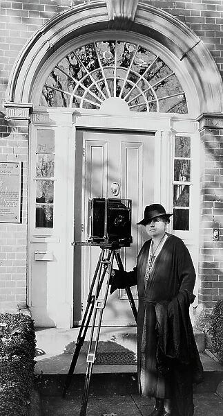 Frances Benjamin Johnston, full-length portrait, standing in front of door, with camera... c1935. Creator: Unknown