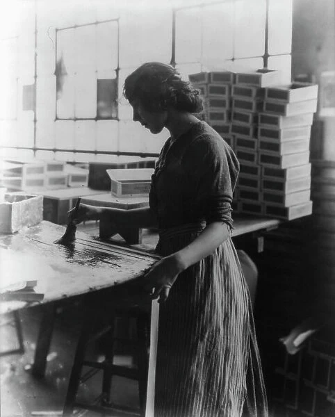 Girl painting strips with glue to assemble cigar boxes, c1910. Creator: Frances Benjamin Johnston