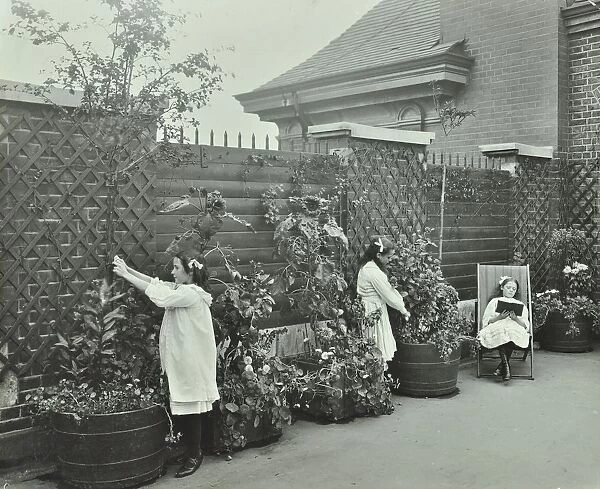 Girls gardening and reading in a roof top garden, White Lion Street School, London, 1912